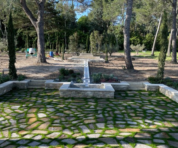 Fontaine et dallage en pierre dans un jardin à Bellegarde